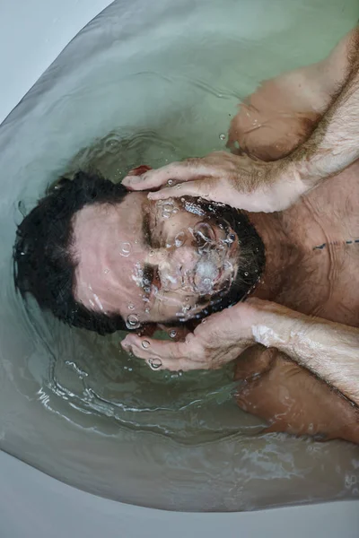 Разочарованный депрессивный человек с бородой тонет в ванне во время поломки, психическое здоровье осведомленности — стоковое фото