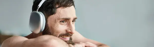 Веселий чоловік з бородою і навушниками сидить і розслабляється у ванній, психічне здоров'я, банер — стокове фото