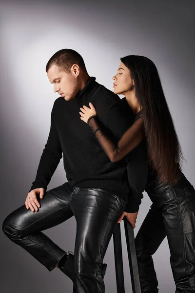 Alla moda asiatica donna calmante sconvolto giovane uomo seduto su sfondo grigio, amore e rapporto — Foto stock