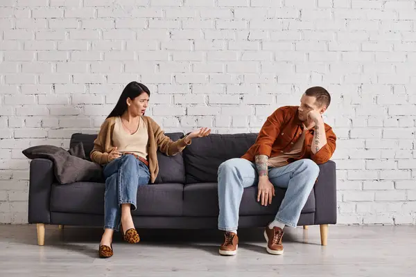 Displeased interracial couple sitting on couch in living room at home, family divorce concept — Stock Photo