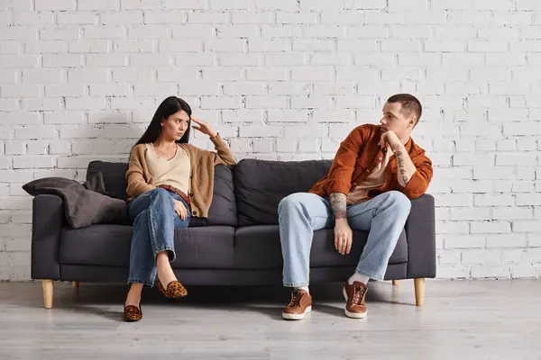 Offeso coppia interrazziale guardando l'altro sul divano in soggiorno, difficoltà di relazione — Foto stock