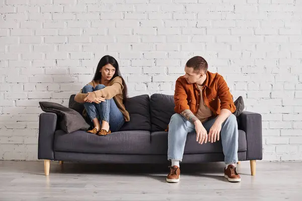 Frustrata coppia interrazziale guardando l'un l'altro sul divano in soggiorno, concetto di divorzio — Foto stock