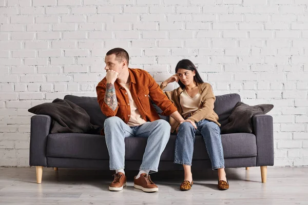 Jeune couple interracial dans la querelle assis sur le canapé dans le salon à la maison, concept de divorce — Photo de stock