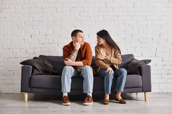 Family divorce, offended asian woman talking to smiling skeptical husband on couch in living room — Stock Photo