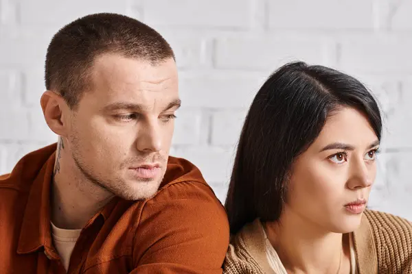 Upset young man looking at young offended asian wife in living room at home, family divorce — Stock Photo