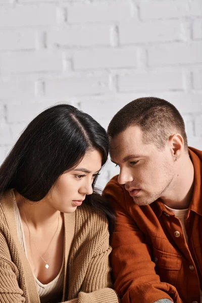 Jovem e deprimido casal multiétnico conversando na sala de estar em casa, dificuldades de relacionamento — Fotografia de Stock