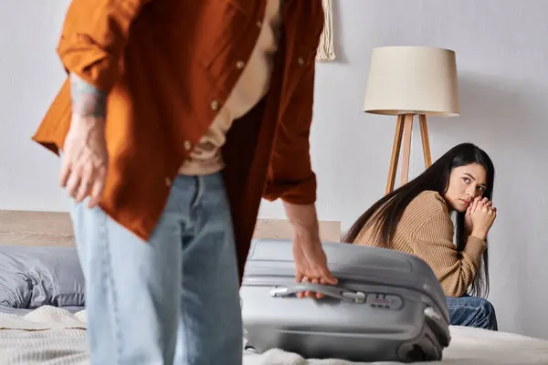 Déprimé asiatique femme assis sur lit et regarder mari emballage valise, divorce concept — Photo de stock