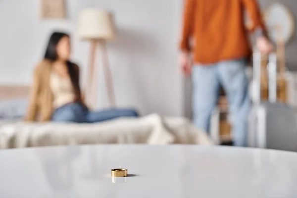 Selective focus of wedding ring on table near interracial couple quarreling in bedroom, divorce — Stock Photo