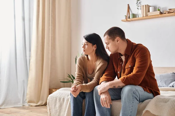 Giovane coppia multietnica frustrato seduto e parlando sul letto a casa, difficoltà di relazione — Foto stock