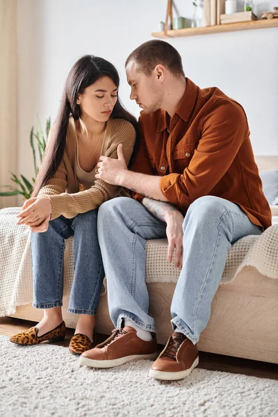 Jeune et tatoué homme parler à bouleversé asiatique femme dans chambre à coucher à la maison, famille trouble concept — Photo de stock