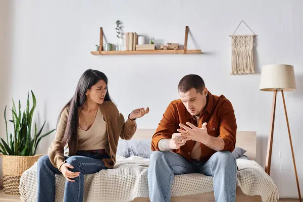 Jeune homme tatoué assis et querelle à la femme asiatique dans la chambre à coucher à la maison, concept de divorce — Photo de stock