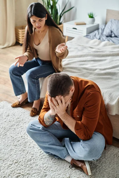 Irritated asian woman quarrelling at husband sitting with bowed head on floor, divorce concept — Stock Photo
