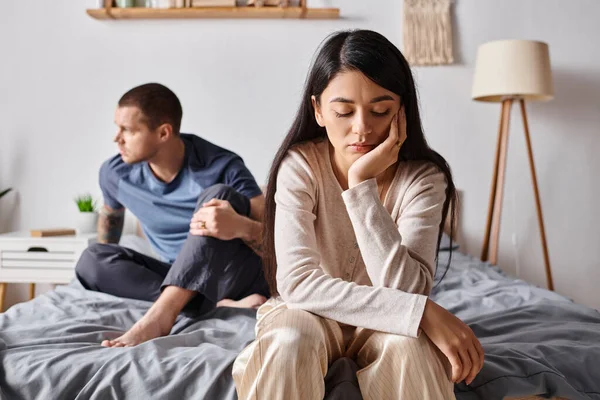 Giovane e frustrato coppia interrazziale seduta in camera da letto a casa, difficoltà di relazione — Foto stock