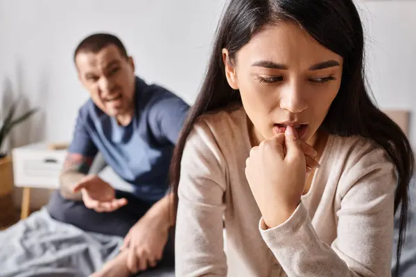 Jeune frustré asiatique femme assis près de colère mari dans querelle dans chambre à coucher, divorce concept — Photo de stock