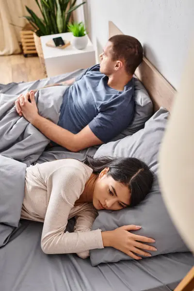 Vista ad alto angolo di giovane e sconvolto coppia interrazziale sdraiato sul letto a casa, problemi familiari — Foto stock