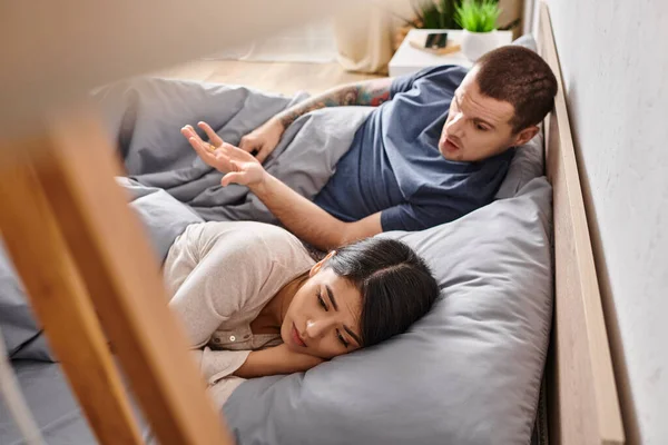 High angle view of irritated man quarreling at upset asian wife on bed at home, divorce concept — Stock Photo