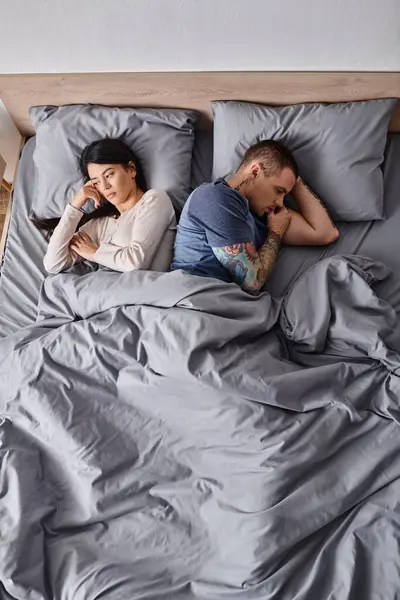 Vista ad alto angolo della coppia interrazziale depressa sdraiata sul letto a casa, concetto di divorzio familiare — Foto stock