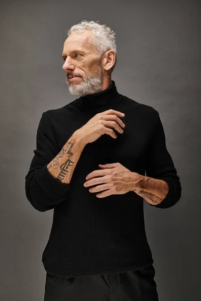 Attrayant homme mature à la mode à col roulé à la mode posant et regardant loin sur fond gris — Photo de stock