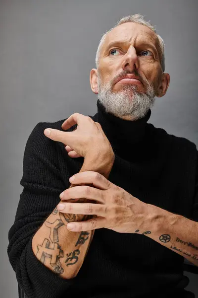 Handsome mature male fashionista with gray beard in chic black turtleneck posing and looking away — Stock Photo