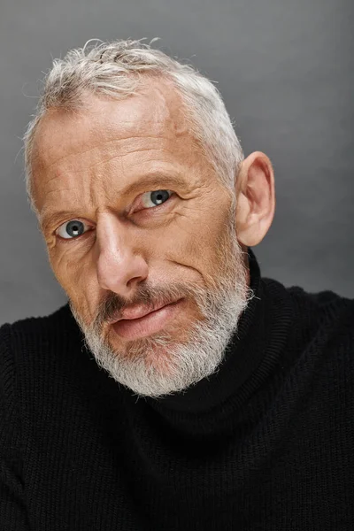 Portrait of handsome bearded mature male model in fashionable black turtleneck looking at camera — Stock Photo