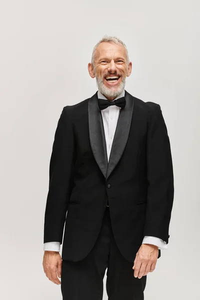 Bonito alegre maduro homem no preto elegante smoking com laço gravata sorrindo feliz para a câmera — Fotografia de Stock