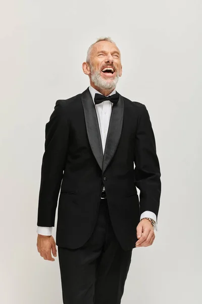 Freudig gut aussehender reifer Mann mit Fliege und grauem Bart im schicken Smoking, glücklich lächelnd — Stockfoto