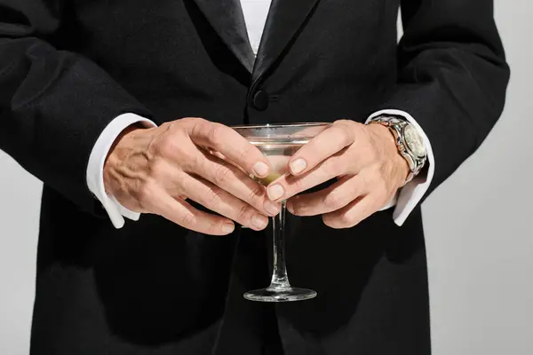 Vista ritagliata di vetro di deliziosi martini con olive verdi in esso nelle mani di uomo maturo ed elegante — Foto stock