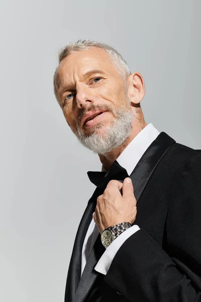 Good looking elegant mature man with beard wearing fashionable tuxedo and looking at camera — Stock Photo