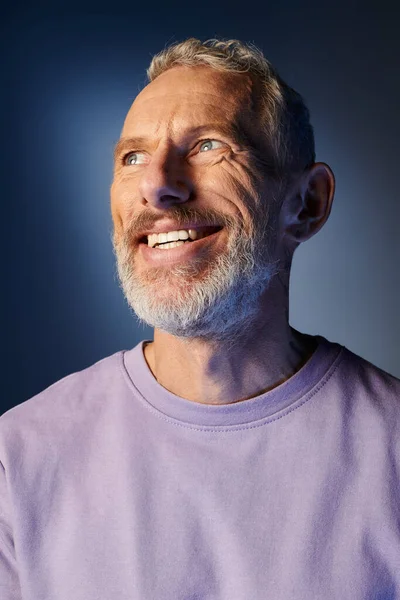 Весёлый бородатый взрослый мужчина в повседневной фиолетовой толстовке с аксессуарами, улыбающимися и отворачивающимися — стоковое фото