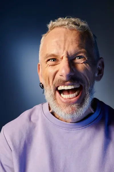 Cheerful mature man with gray beard and casual trendy attire grimacing and looking at camera — Stock Photo