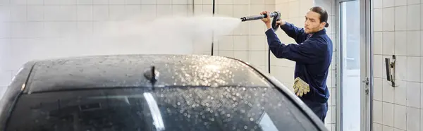Attraktive engagierte Spezialist in blauer Uniform mit gesammelten Haar waschen sorgfältig schwarzes Auto — Stockfoto