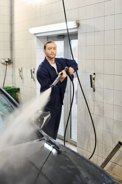 Atraente trabalhador duro serviceman em uniforme confortável com coletado cabelo lavagem carro com cuidado — Fotografia de Stock