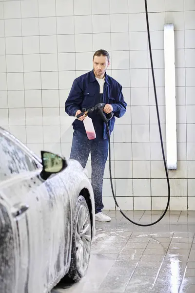 Trabalhador profissional de boa aparência em uniforme com cabelo recolhido lavagem carro moderno preto com sabão — Fotografia de Stock