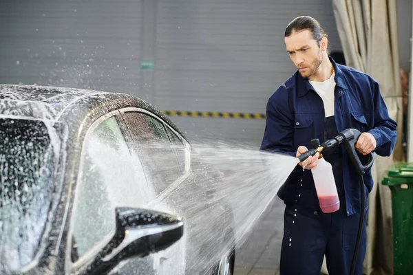 Appealing concentrated handsome man with collected hair in blue uniform washing black car with soap — Stock Photo