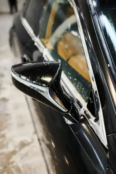 Objektfoto des seifig glänzenden Seitenspiegels eines schwarzen modernen Autos während des Waschvorgangs in der Garage — Stockfoto