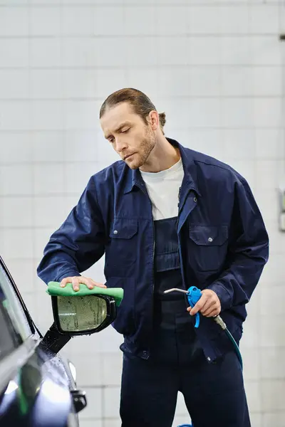 Atraente dedicado profissional serviceman em azul uniforme limpeza preto moderno carro com pano — Fotografia de Stock