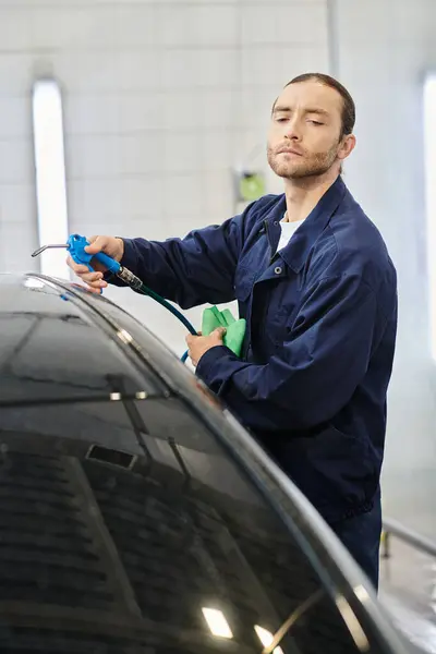 Attractive devoted professional with collected hair washing car with hose and rag in garage — Stock Photo