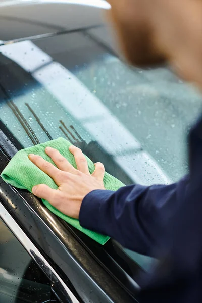 Cropped view of dedicated professional worker in uniform using rag to clean black modern car — Stock Photo
