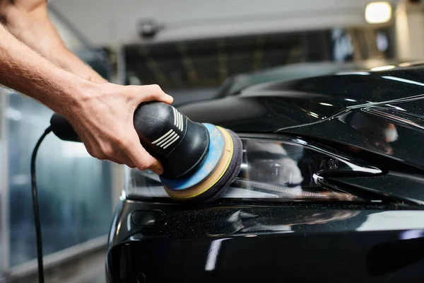 Cropped view of hard working enthusiastic serviceman in uniform using polishing machine on car — Stock Photo
