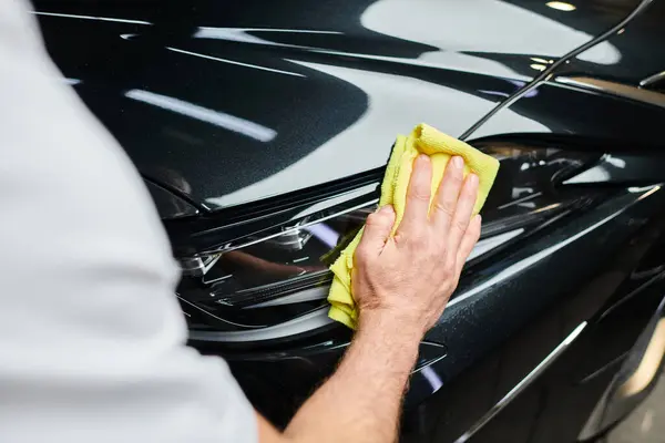 Cropped view of hard working professional serviceman cleaning car with rag while in garage — Stock Photo