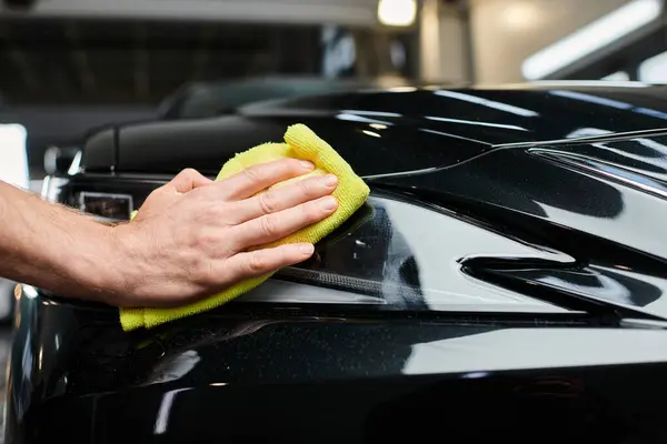 Cropped view of professional dedicated serviceman using small rag to clean black modern car — Stock Photo