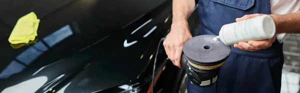 Обрізаний вид відданого професійного працівника в уніформі нанесення полірувальної пасти на машину, банер — стокове фото