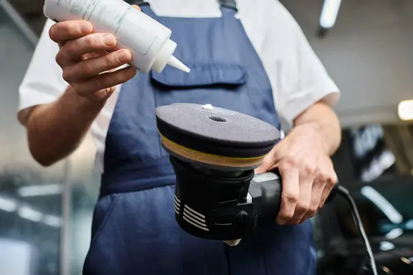 Cropped view of professional dedicated worker in comfy uniform applying paste on polishing machine — Stock Photo