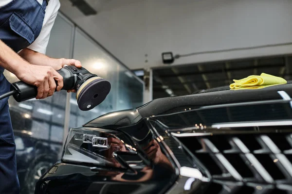 Cropped view of professional hard working specialist using polishing machine on black modern car — Stock Photo