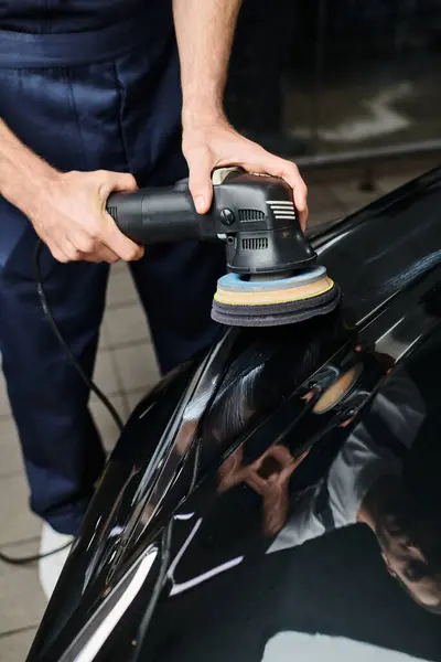 Vista cortada do trabalhador profissional dedicado usando a máquina de polimento com cuidado no carro preto — Fotografia de Stock