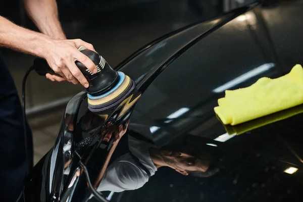 Cropped view of hard working professional specialist working with polishing machine on black car — Stock Photo