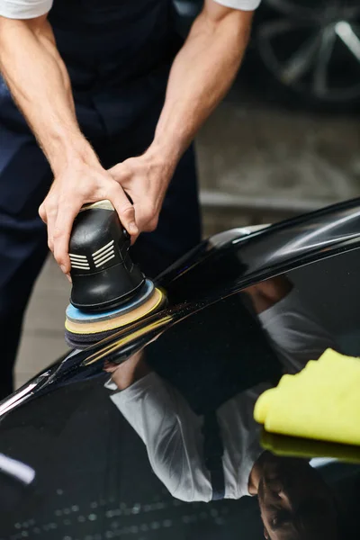 Vista ritagliata di duro lavoro professionale serviceman utilizzando lucidatrice su auto moderna nera — Foto stock