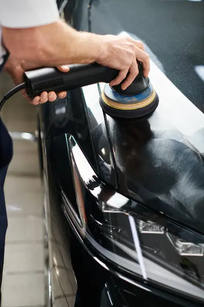 Vue recadrée d'un militaire professionnel dévoué utilisant une machine à polir sur une voiture moderne noire — Photo de stock