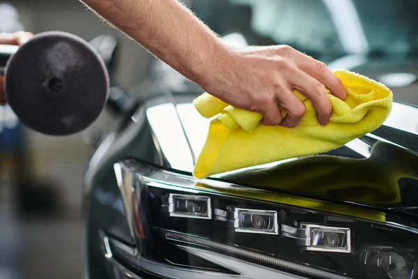 Cropped view of hard working professional serviceman with polishing machine cleaning car with rag — Stock Photo
