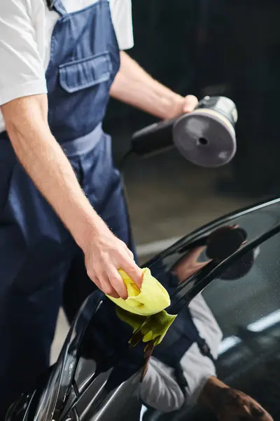 Vista cortada de especialista dedicado limpeza moderna carro preto com pano segurando máquina de polimento — Fotografia de Stock